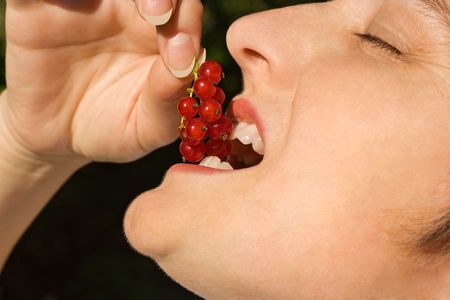 Young woman tasting redcurrantの写真素材