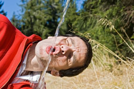 Young man drinking cold fresh waterの写真素材