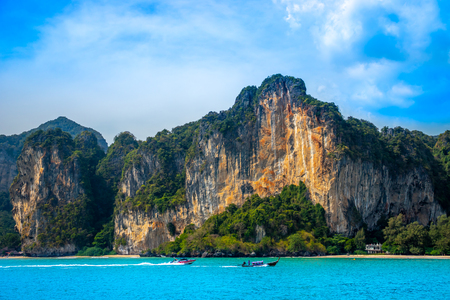A thai long-tail boat and a motorboat racing along beautiful limestone mountains near Railay Beach in Krabi along the Andaman coast of Thailand.の写真素材