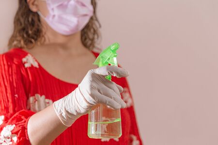 Latin woman taking precautions by covid-19 wear a face mask, gloves and sprayer to prevent infection