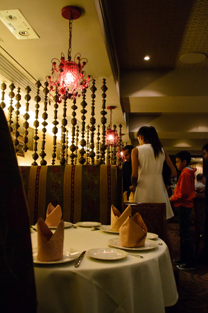 Table setting with napkins in Indian restaurant and hanging lightsのeditorial素材