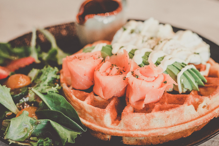 Homemade waffle with smoked salmon and sliced avocado and poached eggsの写真素材
