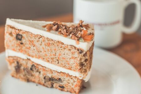Classic American Carrot Cake with cream cheese frosting and a cup of hot latteの写真素材