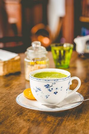 green tea matcha soy latte in a china cup with brown sugar and a glass of water on the sideの写真素材
