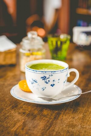 green tea matcha soy latte in a china cup with brown sugar and a glass of water on the sideの写真素材