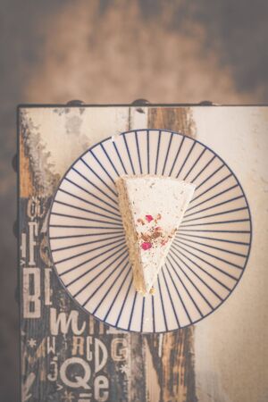 pistachio rose cake with pistachio bits and rose flavoured cream served on a colourful plate in a cafeの写真素材