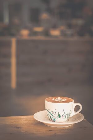 cappucino with leaf design latte art in a porcelain cup and saucer in a cafeの写真素材
