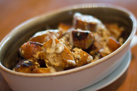 Spiced roasted pumpkin with savoury granola and yoghurt in a white porcelain dishの写真素材