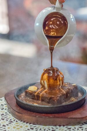 hot chocolate brownie on sizzling hot plate with vanilla ice cream and topped with almond flakes and hot chocolate sauceの写真素材