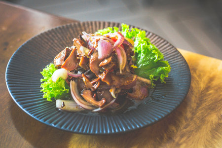 Topshell with onion and chilli padi tossed in special spicy sauces served in a black dishの写真素材