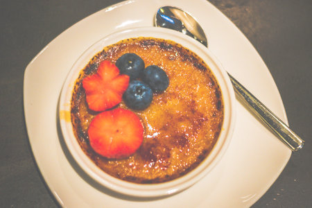 Creme Brulee served with strawberry, blueberries, a teaspoon on a white dishの写真素材