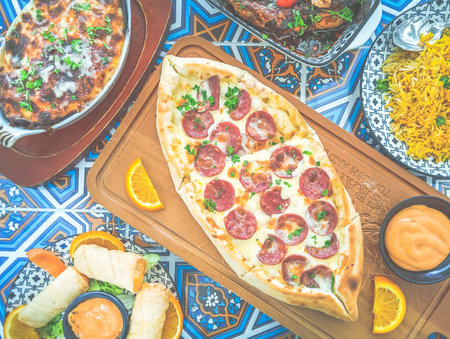 a platter of middle eastern food such as pide, cheese rolls, Fesenjan stew, stuffed baked aubergine