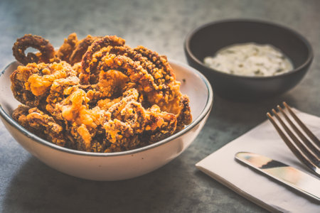 Fried Octopus  tentacles in a bowl with tartar sauce on the sideの写真素材
