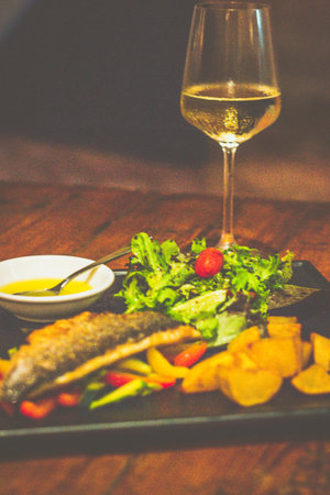 GRILLED ITALIAN SEABASS Served with sauteed vegetables and roasted potatoesの写真素材