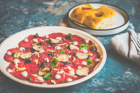 Angus Beef Carpaccio Thinly sliced raw Australian beef shaved fresh seasonal truffle, Italian truffle puree, sliced Grana Padano cheese, bread on the sideの写真素材