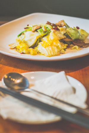 Stir Fried Cabbage with Cabbage, pork belly, dried chilli served in a white plateの写真素材