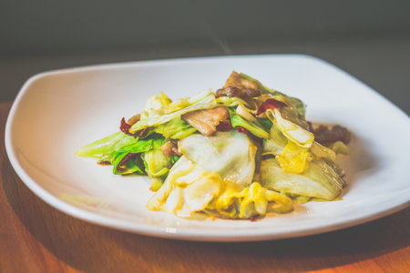 Stir Fried Cabbage with Cabbage, pork belly, dried chilli served in a white plateの写真素材