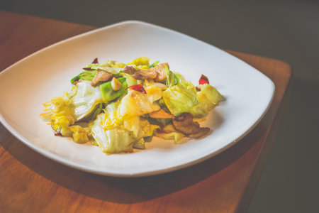 Stir Fried Cabbage with Cabbage, pork belly, dried chilli served in a white plateの写真素材