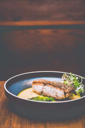 pan fried Sea Bass fillet with saffron sauce and green asparagus in a blue bowlの写真素材