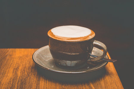 a cup of cappucino with white milk foam on top in a brown cup
