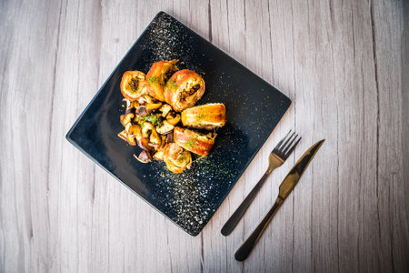 chicken roulade with sauteed mushrooms served on a black platterの写真素材