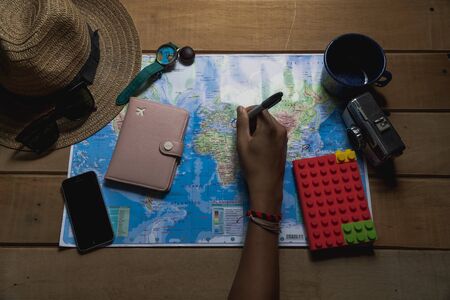 Tourist planning vacation with the help of world map with other travel accessories aroundの写真素材