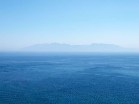 Distant mountains on the horizon surrounded by the endless sea.の写真素材