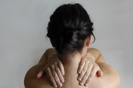 Nude woman with back pain on a gray backgroundの写真素材