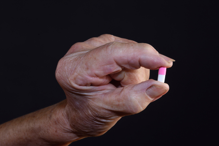 Hand of an old woman with a pill and fungus on the nailsの写真素材