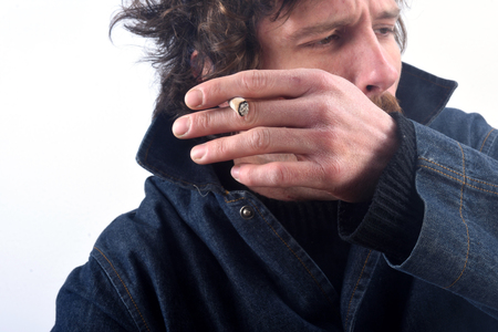 Portrait of a man smoking tobacco and coughing on white backgroundの写真素材