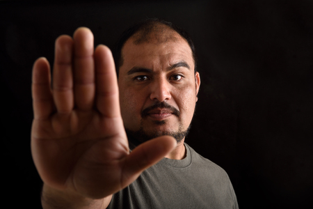 Portrait of a latin man with stop sing on black