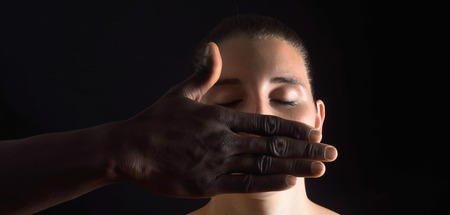 a hand covering  mouth of caucasian woman on black