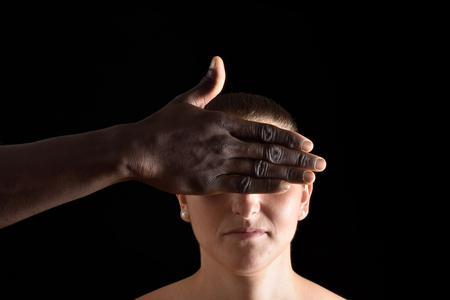 a hand covering  eyes of caucasian woman on blackの写真素材