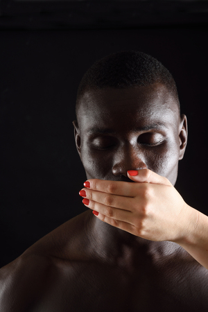 a hand covering  mouth of african man on blackの写真素材