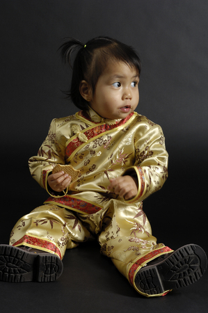 Portrait of a little chinese girl eating a cookieの写真素材
