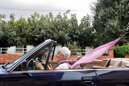old woman driving a convertible carの写真素材