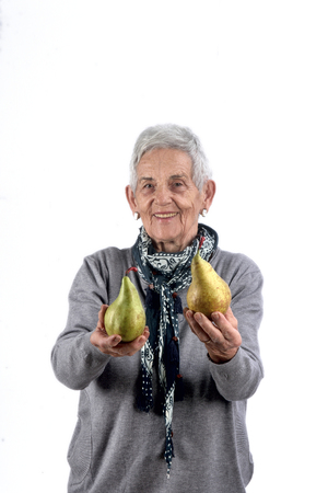 senior woman eating pear on whiteの写真素材