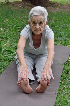 elderly woman practicing yoga outdoorsの写真素材