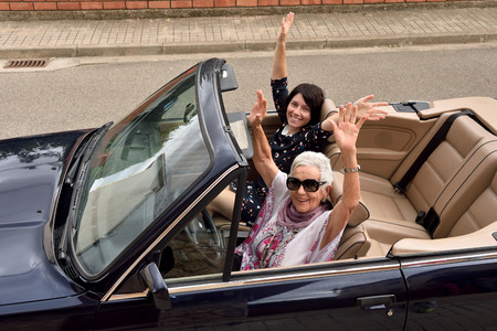 women of different generations happy in a convertible carの写真素材