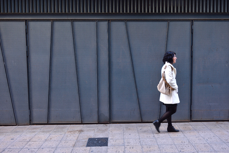 woman walking next to an iron texture wall