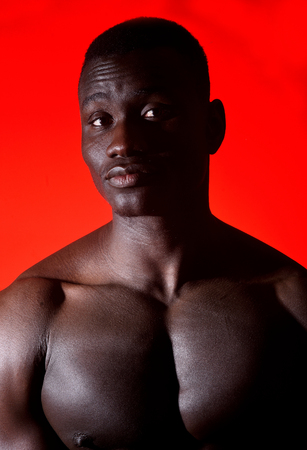 portrait of an african man shirtless on red backgroundの写真素材