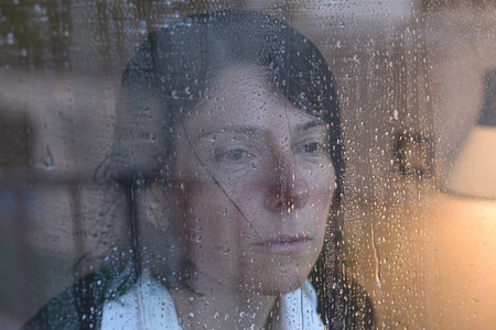 Woman looking out the window on a rainy dayの写真素材