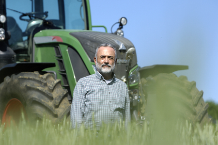 portrait of a farmer with tractor on backgroundの写真素材