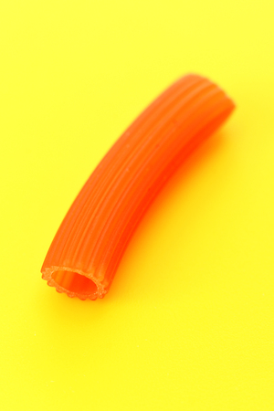 Pasta red macaroni (tomatoes) on yellow background