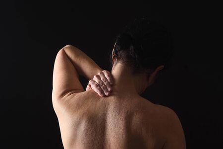 middle-aged woman with pain in the neck on black backgroundの写真素材