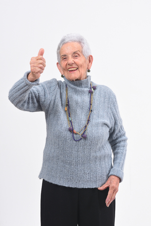 older woman with thumbs up and smile on white backgroundの写真素材
