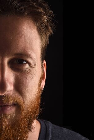 half portrait of a man close up looking at camera on black backgroundの写真素材