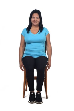 portrait of a woman sitting on a chair in white background, front viewの写真素材