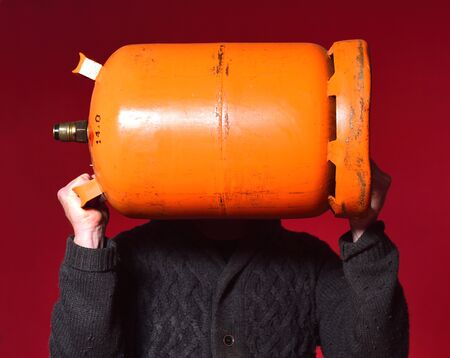 man holding a bottle of butane gas on red backgroundの写真素材
