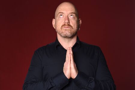 man praying on red background, look up